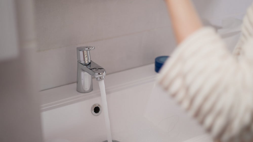 Water flowing from a bathtub spigot, showing a plumbing issue that may require water heater repair.